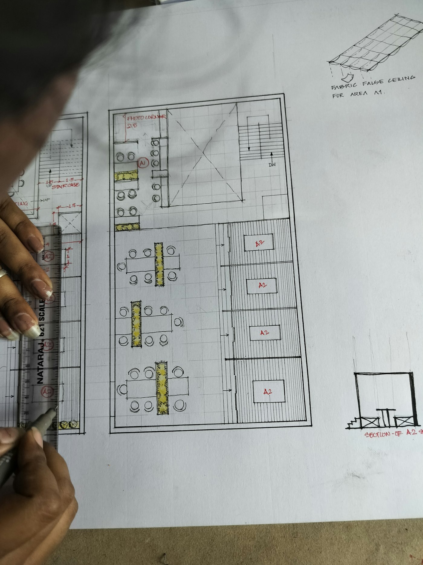 Person drawing an architectural floor plan on paper while planning a construction project